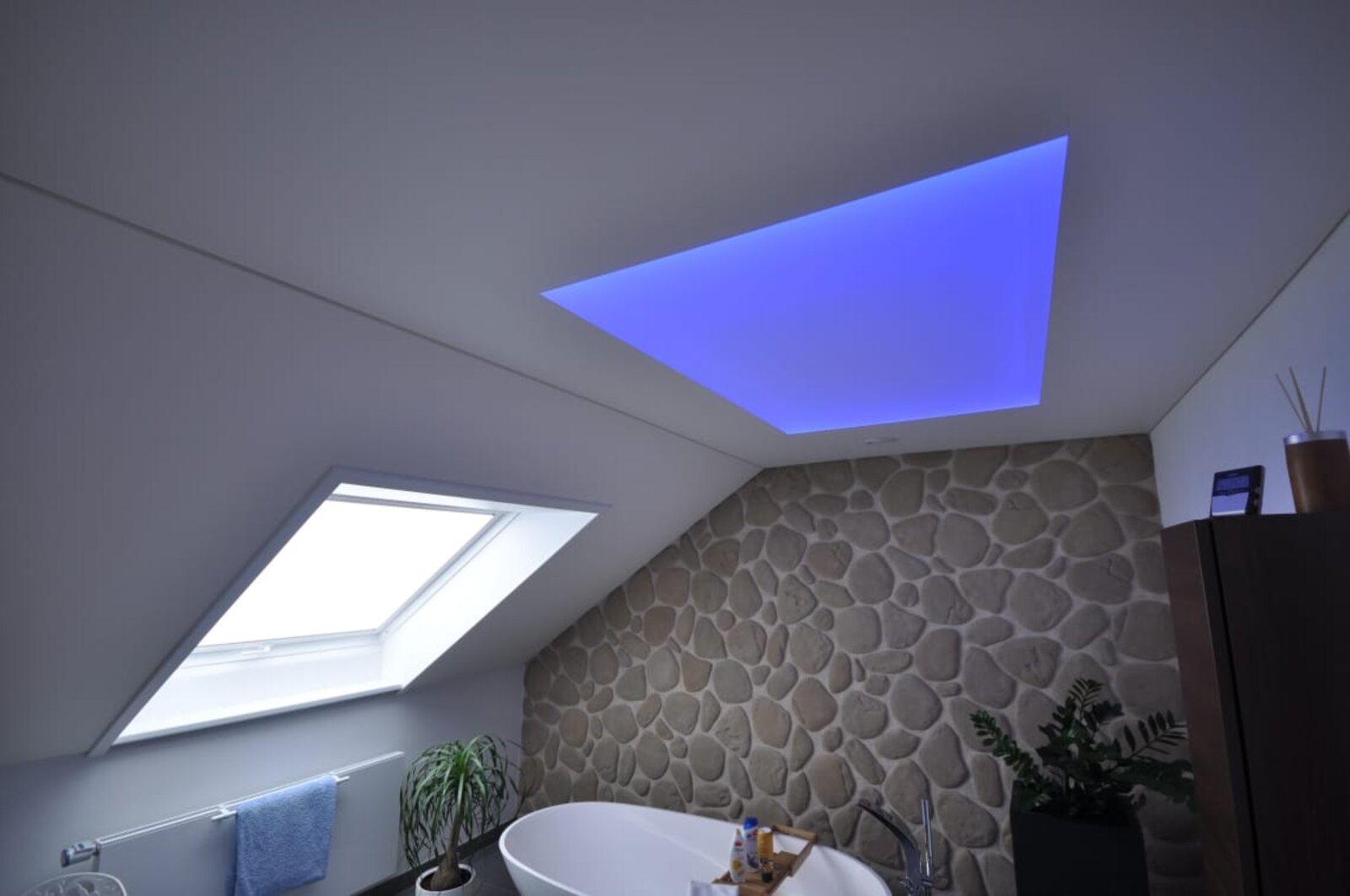 Spanndecke im Bad mit Dachschräge in weiss matt. Beleuchtung mit Deckenfeld als Lichtdecke in LED-RGB