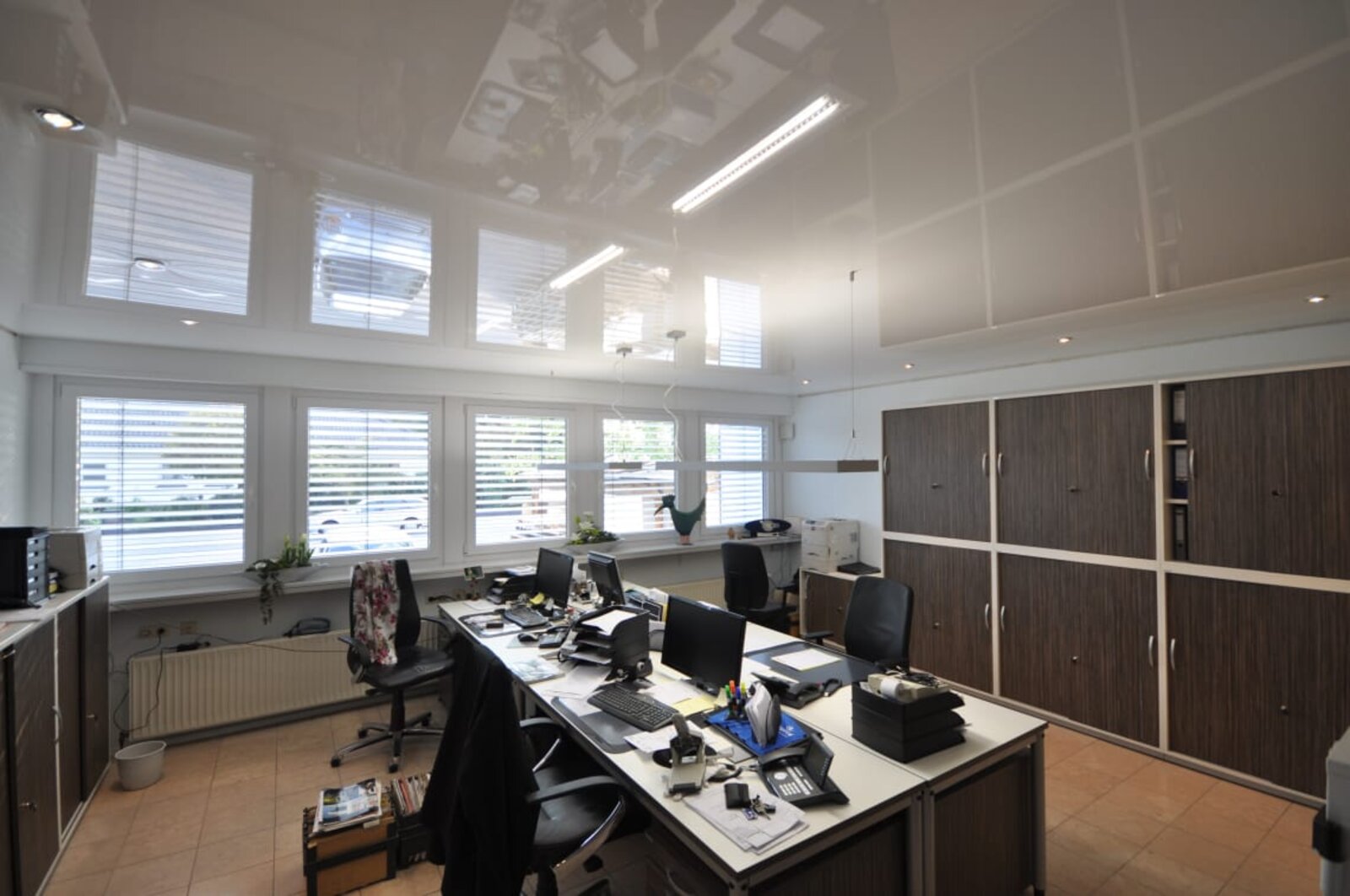 Lackspanndecke im Büro in weiss Hochglanz, Beleuchtung mit LED-Einbaustrahlern und Bildschirmarbeitsplatz-Leuchten über den Arbeitsplätzen