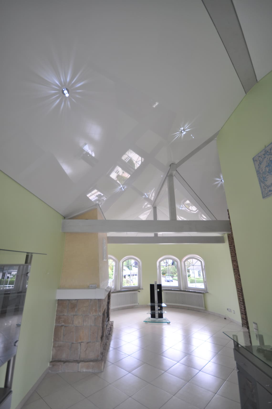 Lackspanndecke im Wohnzimmer mit Dachschräge in weiss Hochglanz. Beleuchtung mit LED-Einbaustrahlern und Swarovski Sternenhimmel