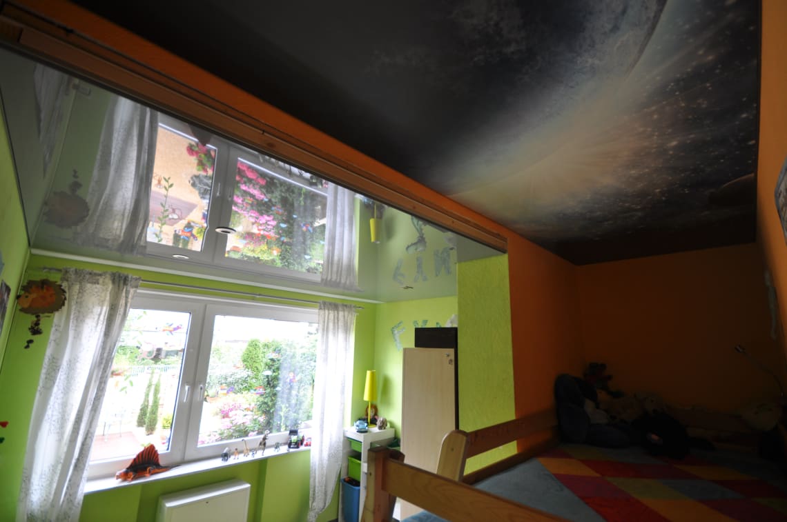 Lackspanndecke in grau Hochglanz und mit Motiv bedruckte Spanndecke im Kinderzimmer. Beleuchtung mit LED-Einbaustrahlern und LED-Band umlaufend hinter der bedruckten Spanndecke
