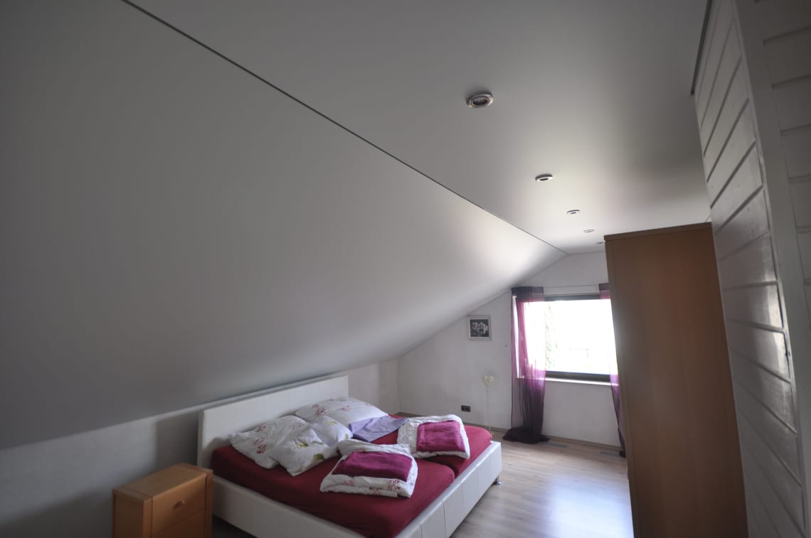 Spanndecke im Schlafzimmer mit Dachschräge in weiss matt. Beleuchtung mit LED-Einbaustrahlern